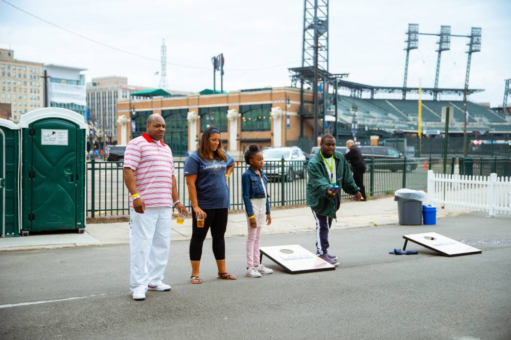 Four members of a gsvu family playing cornhole at the gvsu party right outside of comerica park